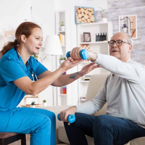 Physiotherapist providing physiotherapy at home to an elderly patient in a comfortable British living room
